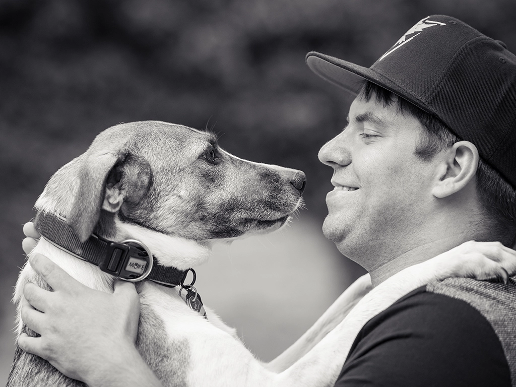 Mein Blick für emotionale Tierporträts: Ein Mensch mit seinem Hund, festgehalten in einem authentischen Moment in Schwarz-Weiß, Teil meiner Arbeit an der Krämerbrücke.